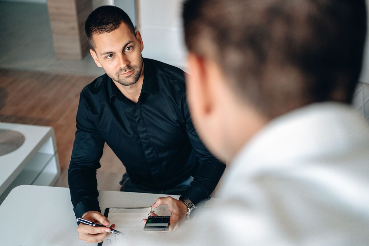 Consultant taking notes while meeting a client across a table